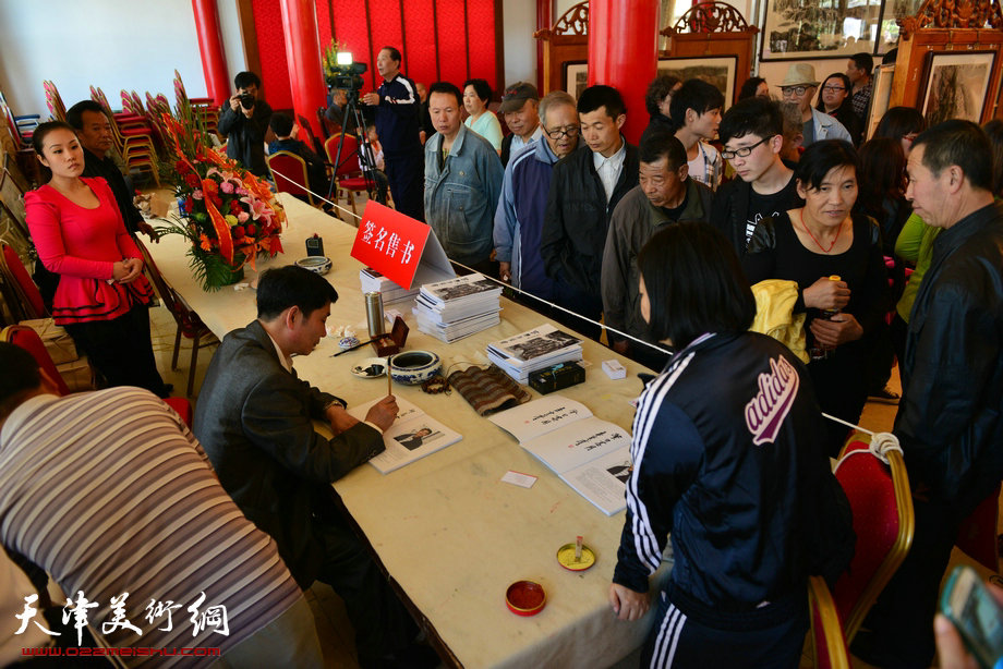 孟宪奎《蒙·大山情》画展“五·一”亮相天津水上公园，图为签售书画集现场。