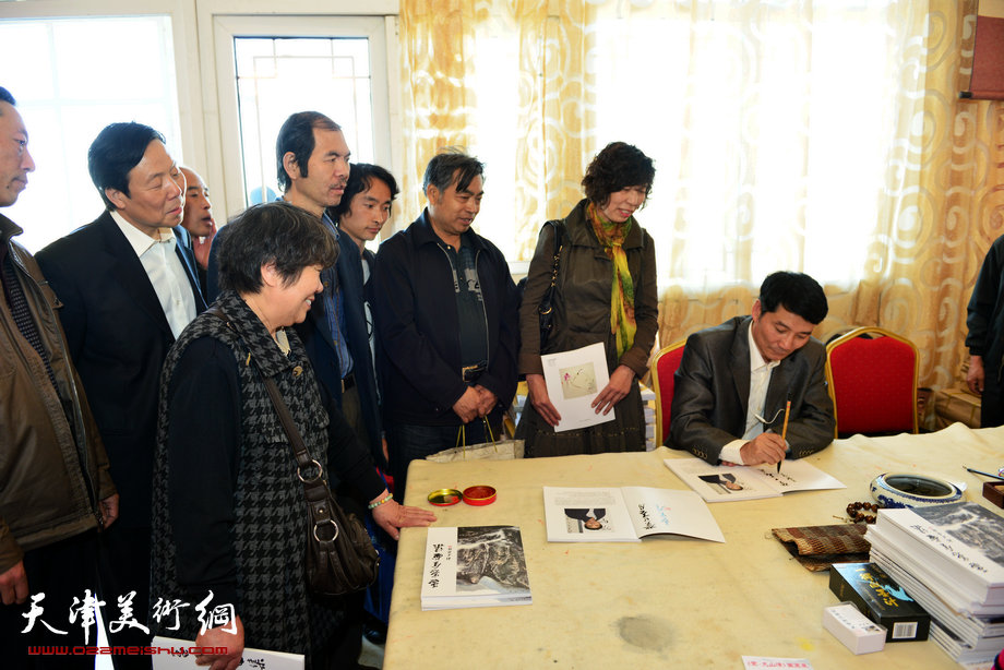 孟宪奎《蒙·大山情》画展“五·一”亮相天津水上公园，图为签售书画集现场。