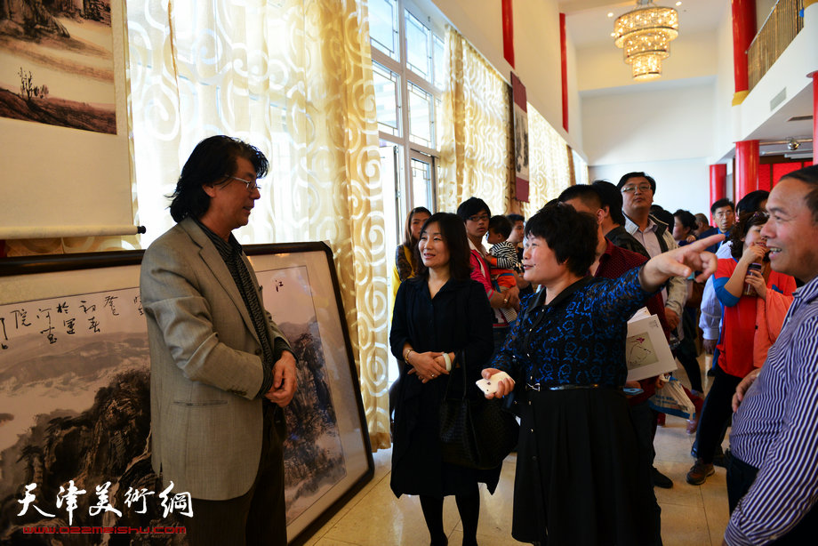 孟宪奎《蒙·大山情》画展“五·一”亮相天津水上公园，图为天津美协副主席郑连群在画展现场与来宾交谈。