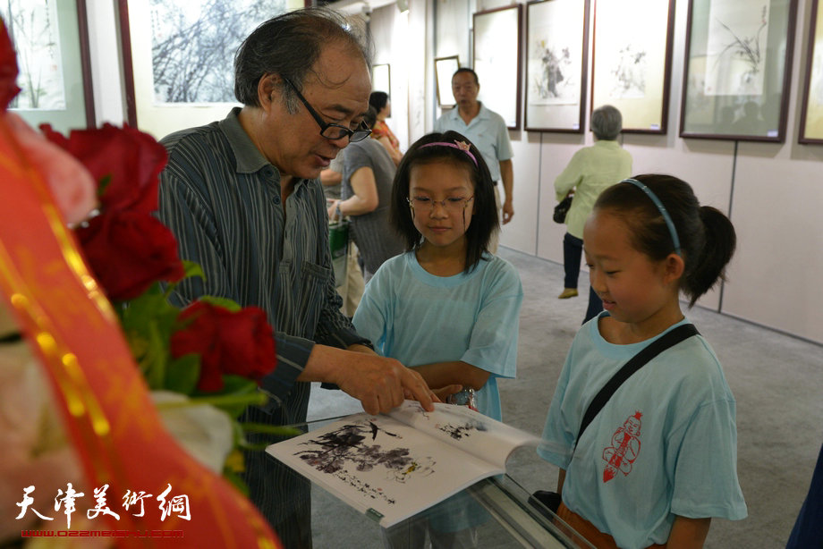 天津花鸟四家师生作品展在图书大厦书天艺苑开幕。图为郭书仁在画展现场为小朋友签名。