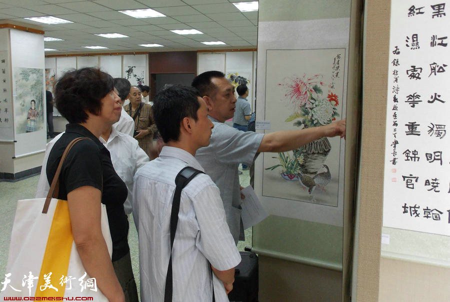 津报书画俱乐部第8届会员展揭幕。图为花鸟画家张国富给会员点评作品