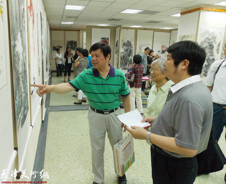 津报书画俱乐部第8届会员展揭幕。图为花鸟画家李根友、王惠民与会员交流创作感想。