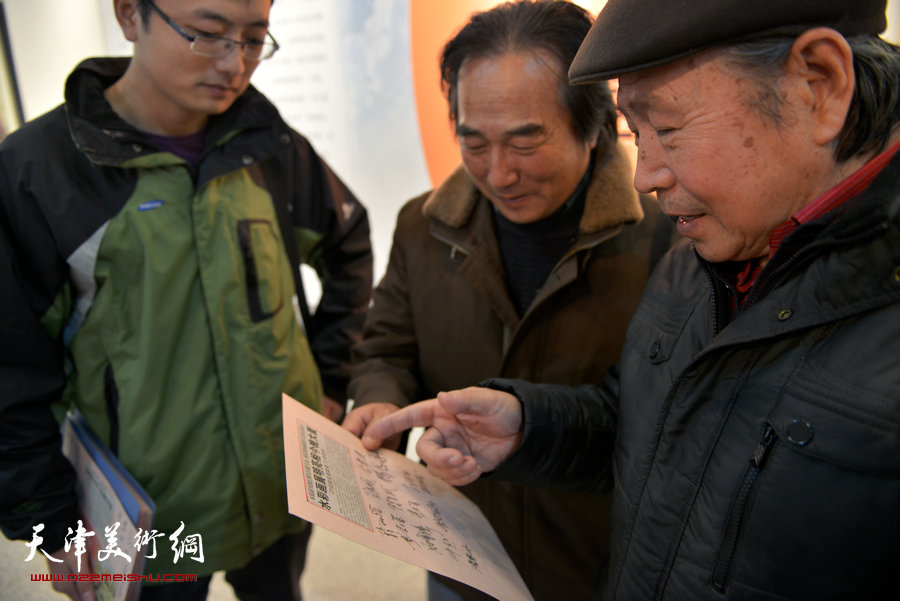 天津第七届水彩画展在财经大学艺术学院展馆举行，图为陈重武、李宗儒在画展现场观看杨颖水彩画集报。