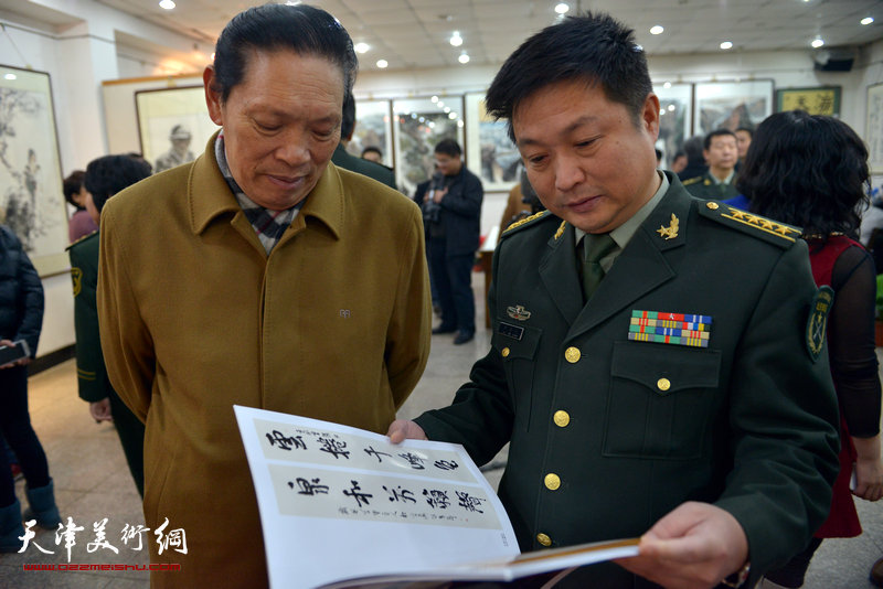 “鱼水情”迎新春书画展在北辰书画院举办，图为任之通在画展现场观看画册。