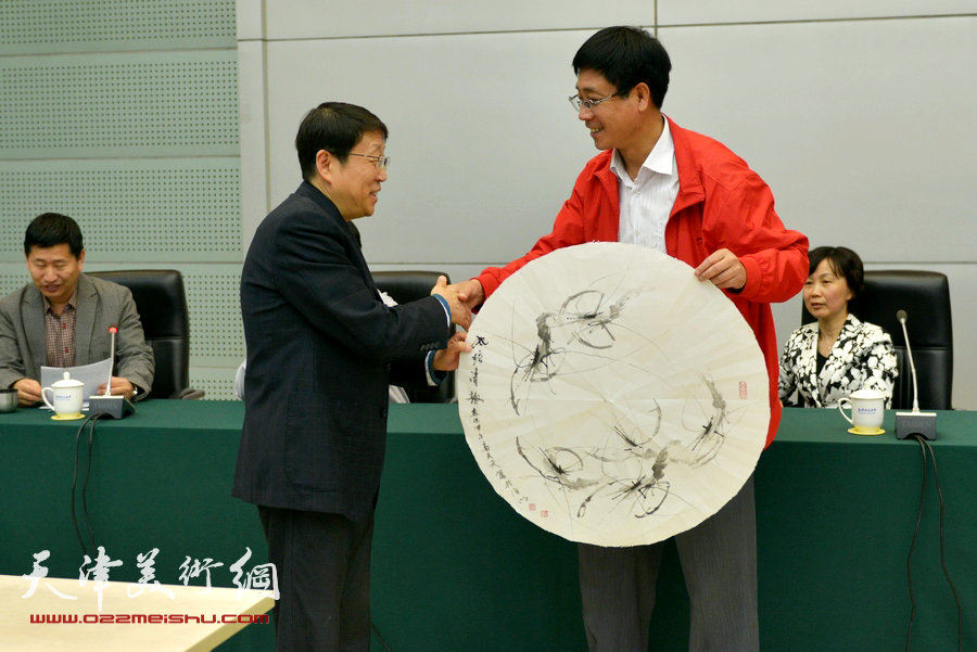 津门书画家慰问劳模笔会在天津师范大学举行，图为高天武向劳模赠送作品。