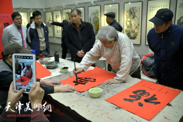 图为师光复在画展现场写福字。