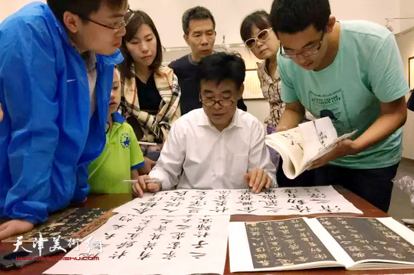 10月6日，李云光先生在书法展上与观众互动交流，为在南开大学历史系读书的香港学生讲解临帖方法