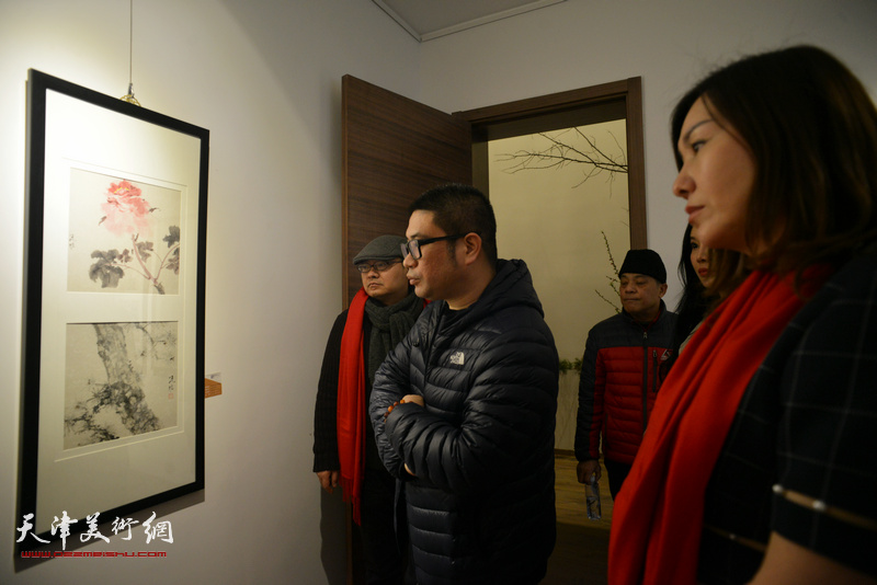 姜立志与来宾观赏展出的画作。