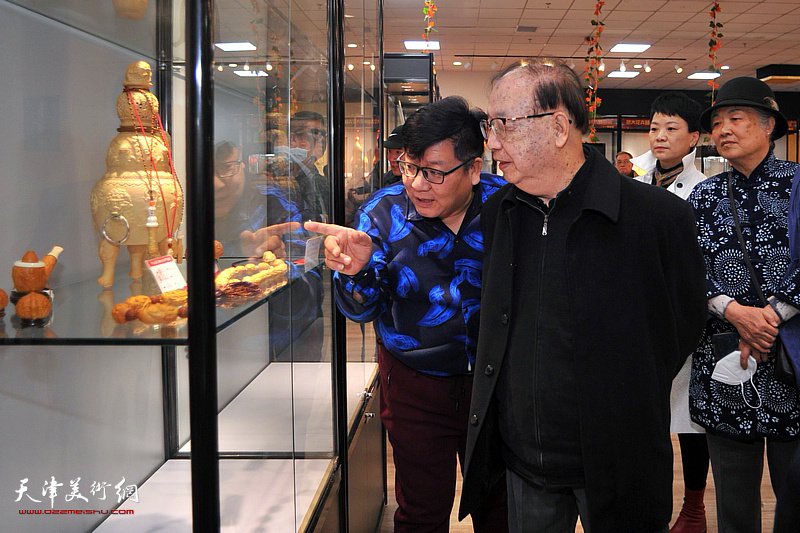 张福来向罗澍伟介绍陈列的葫芦艺术作品。