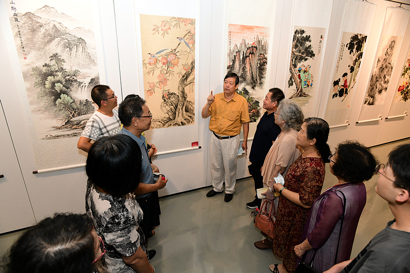 陈元龙向书画爱好者介绍展出的作品。